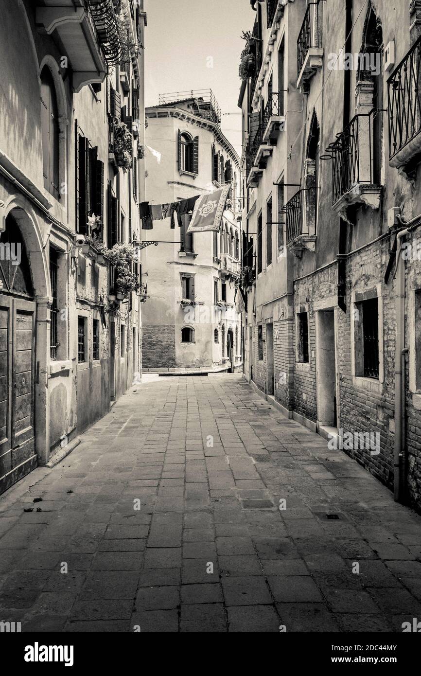 Una tranquilla stradina veneziana con lavaggio asciugando nella piccola brezza. Le strade secondarie di Venezia conducono ad aree inaspettate e inesplorate. Foto Stock