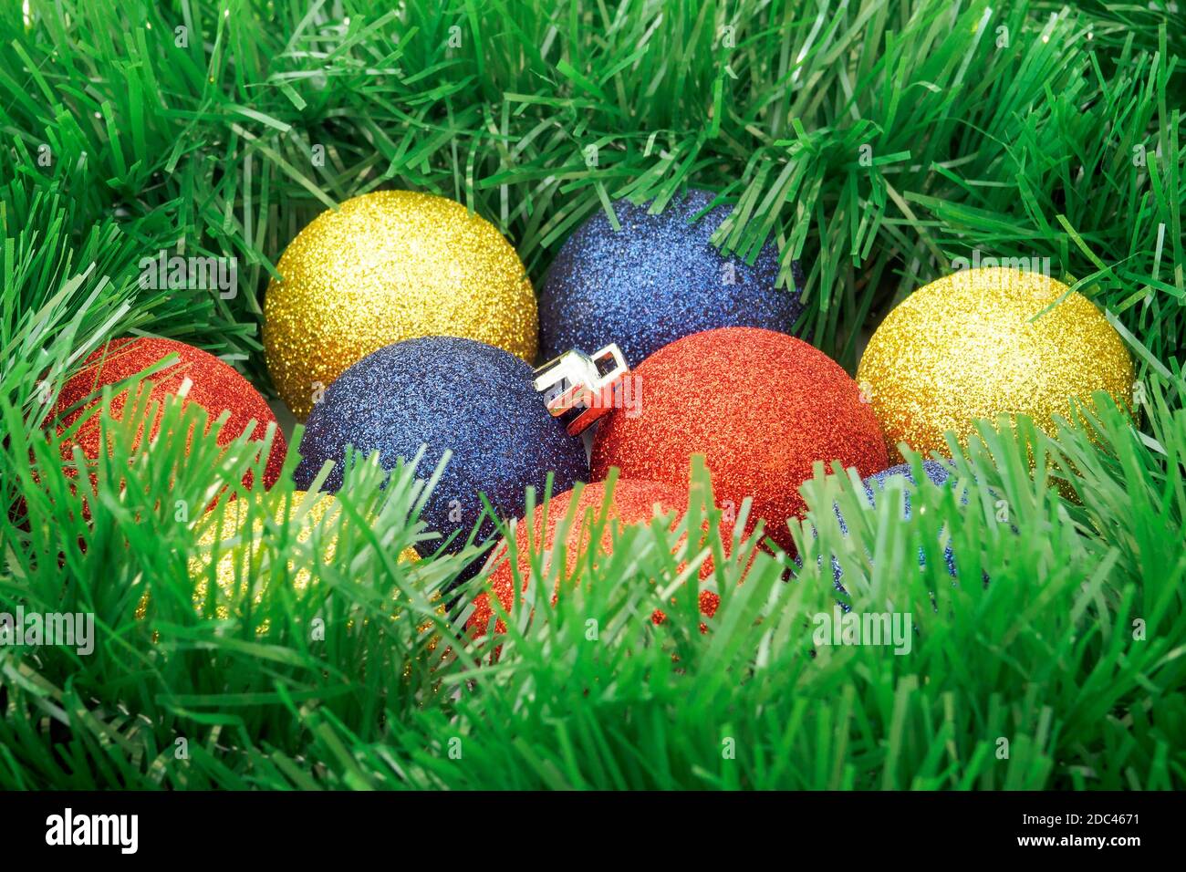 Verde tinsel garland intorno palle di Natale come nido. Messa a fuoco selettiva Foto Stock