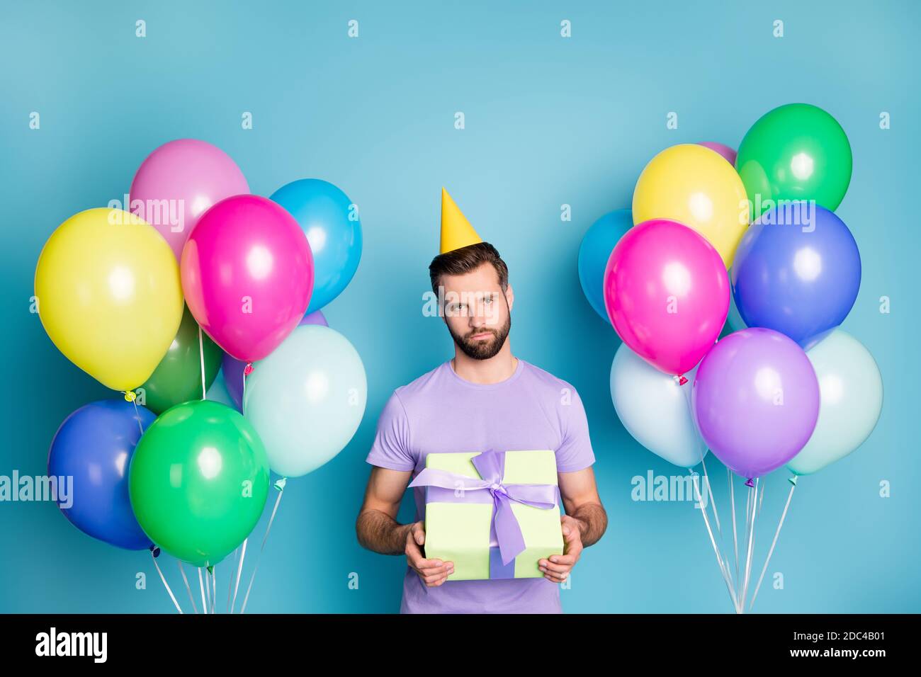 Ritratto fotografico di un ragazzo indifferente che tiene la confezione regalo nessuno è venuto per party isolato su sfondo color blu pastello Foto Stock