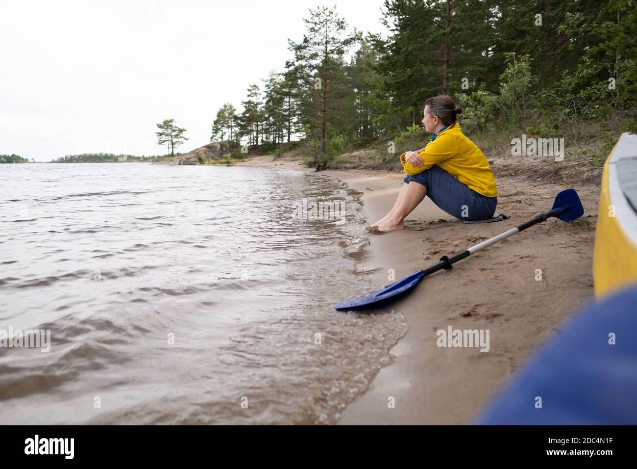 donna caucasica che riposa presso il lago dopo il kayak. Foto Stock