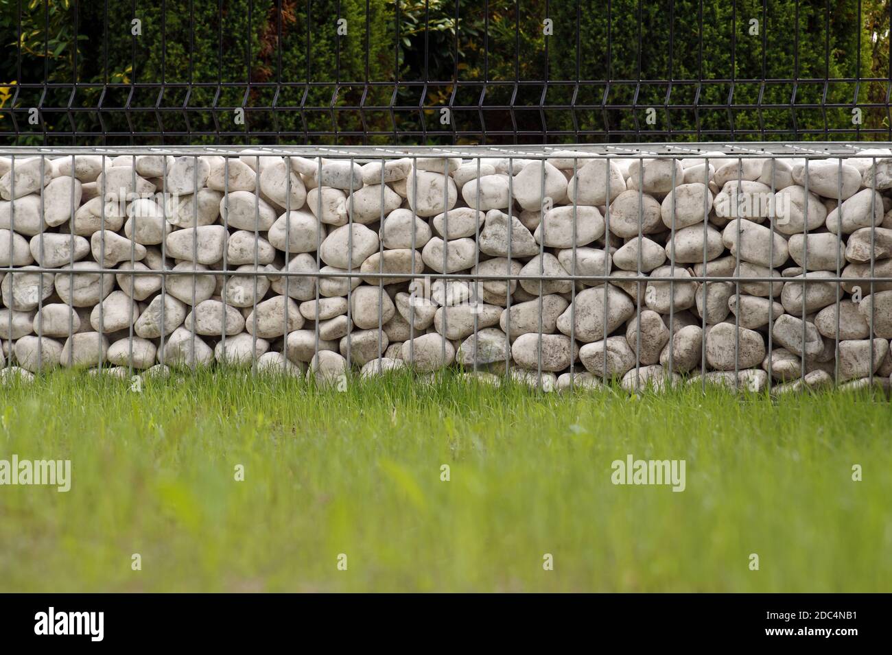 Impressionante modo di recinzione del giardino, cestini in metallo riempiti di ciottoli bianchi. Foto Stock