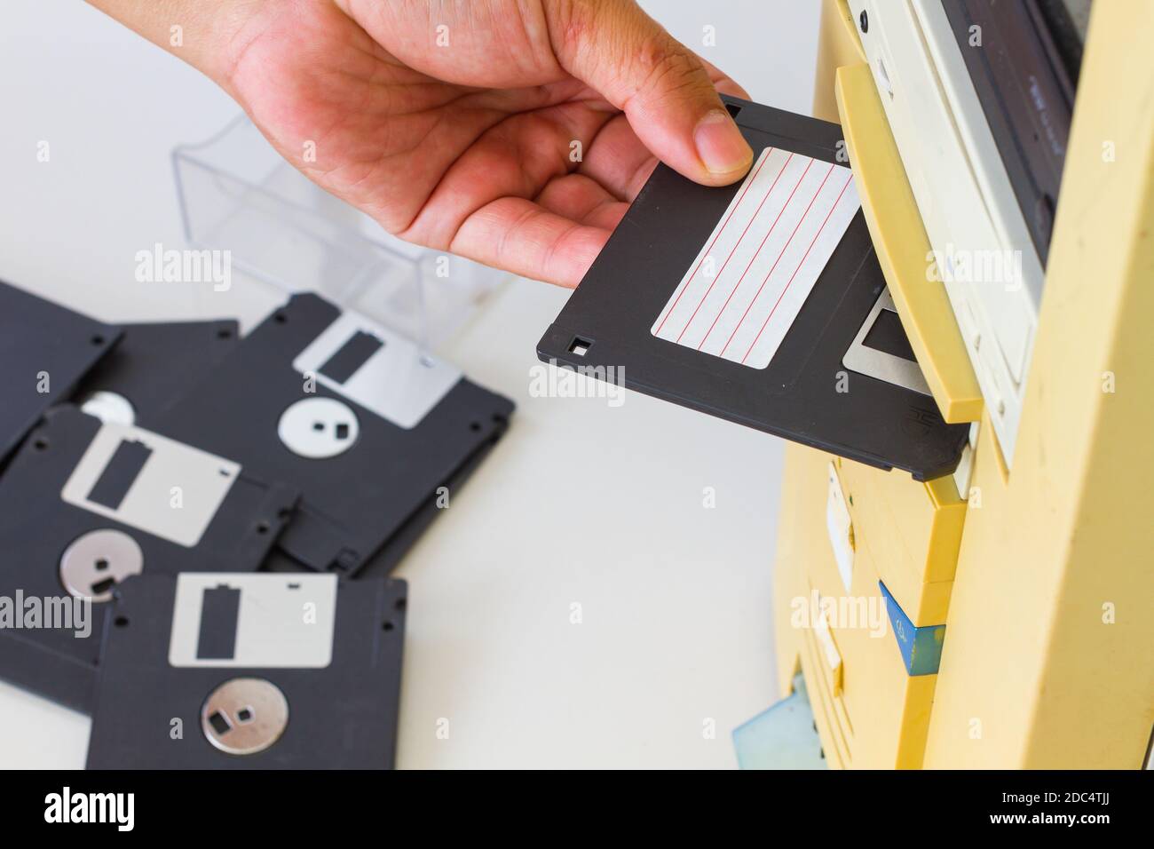 Inserimento manuale di un disco floppy da 3.5 pollici in uno slot per unità floppy su un computer desktop. Messa a fuoco selettiva. Foto Stock