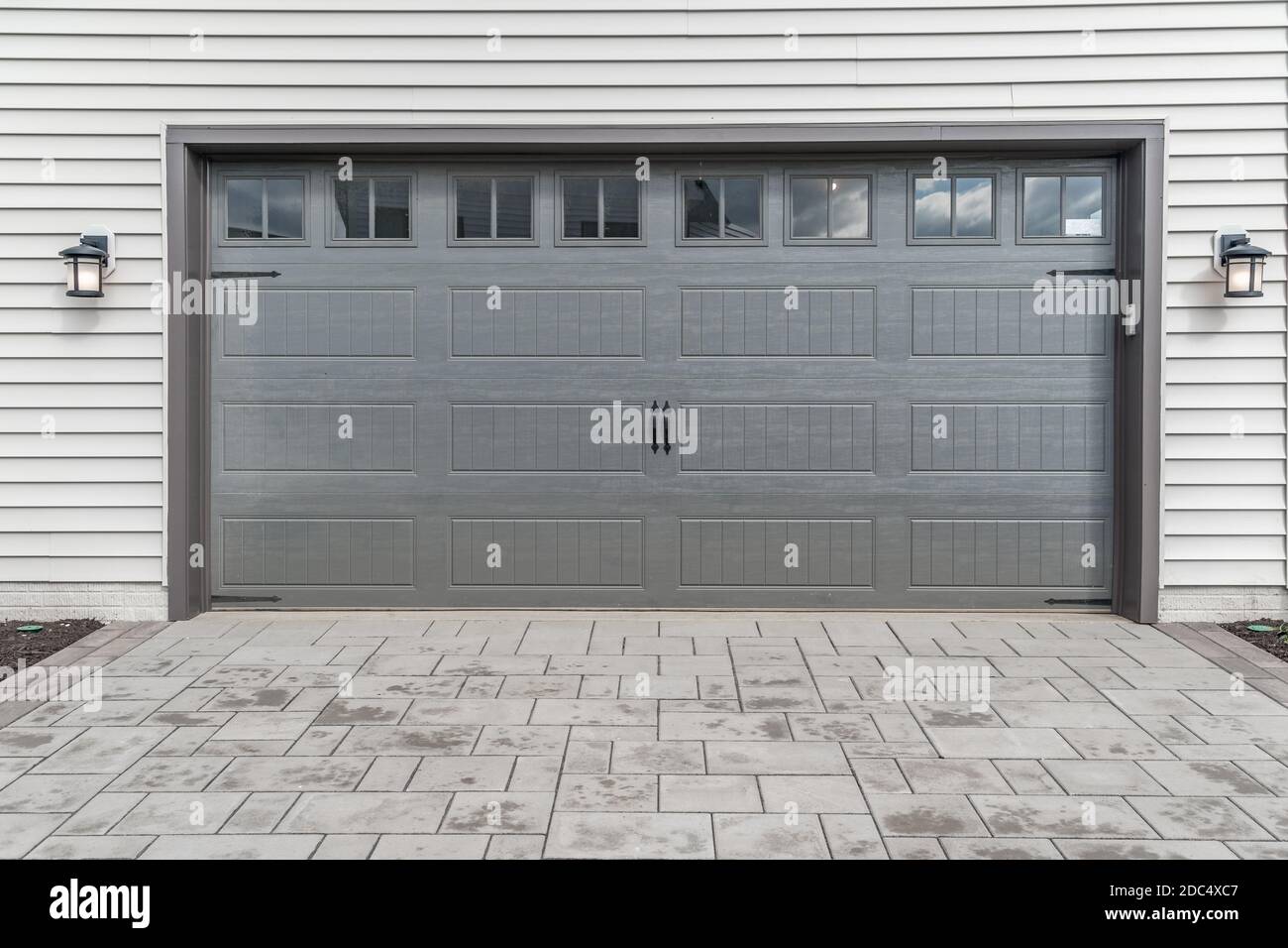Grigio due porta singola garage incorniciata con pietra architettonica per aggiungere accento, con finestre luce specchio diviso da muntins griglie Foto Stock