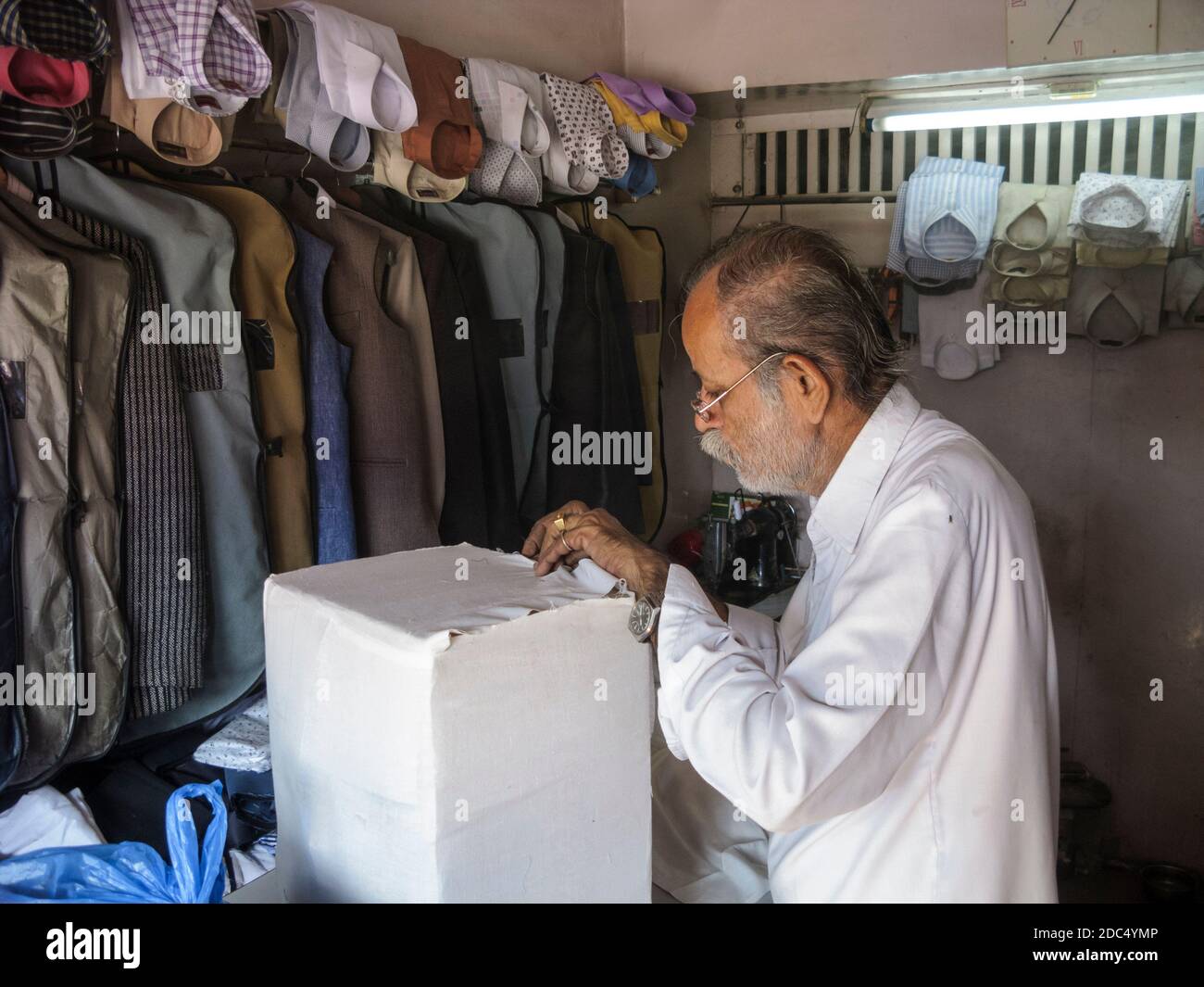 India, Rajasthan, Jodhpur. G. Walior, un negozio di sarto. Sta cucendo un pacco in cotone bianco e sigillando con cera pronto per l'invio in UK per posta. Foto Stock