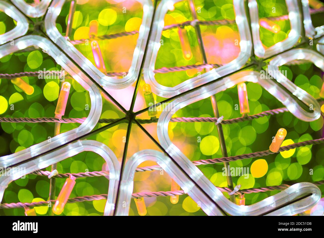 Terreno luminoso a forma di fiocco di neve. Illuminazione notturna della città. Lampadine verdi su ghirlande. Vacanze invernali. Concetto di Natale e Capodanno. Foto Stock