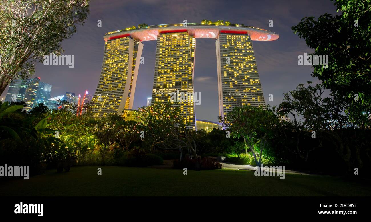 Marina Bay Sands celebra la giornata nazionale di Singapore con la luce che mostra la bandiera nazionale. Catturato dal giardino dalla baia. Foto Stock