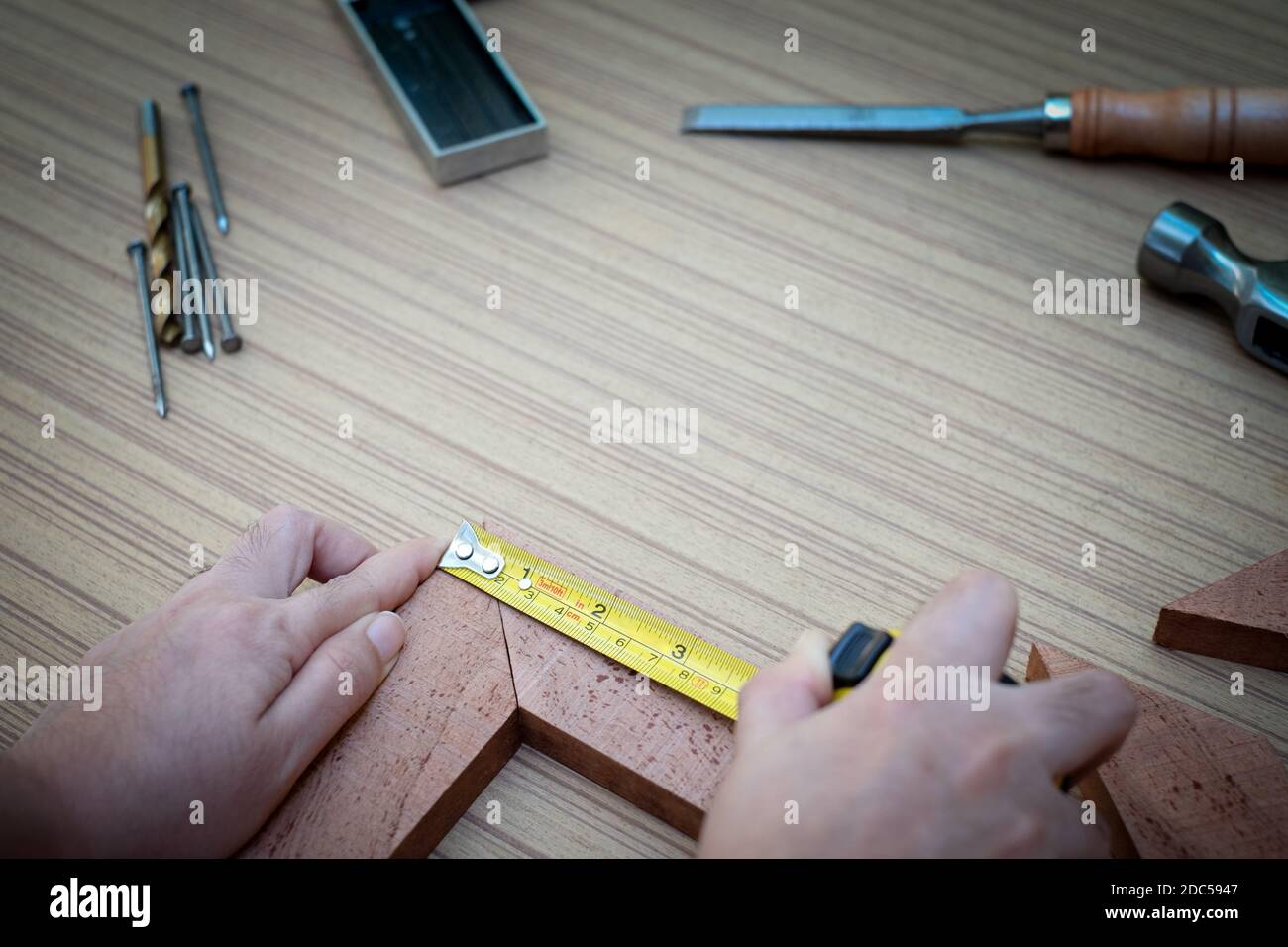 Primo piano delle mani di una donna che misura la tavola di legno con un metro a nastro con una collezione di utensili manuali da lavoro per il legno, set di attrezzi con t Foto Stock
