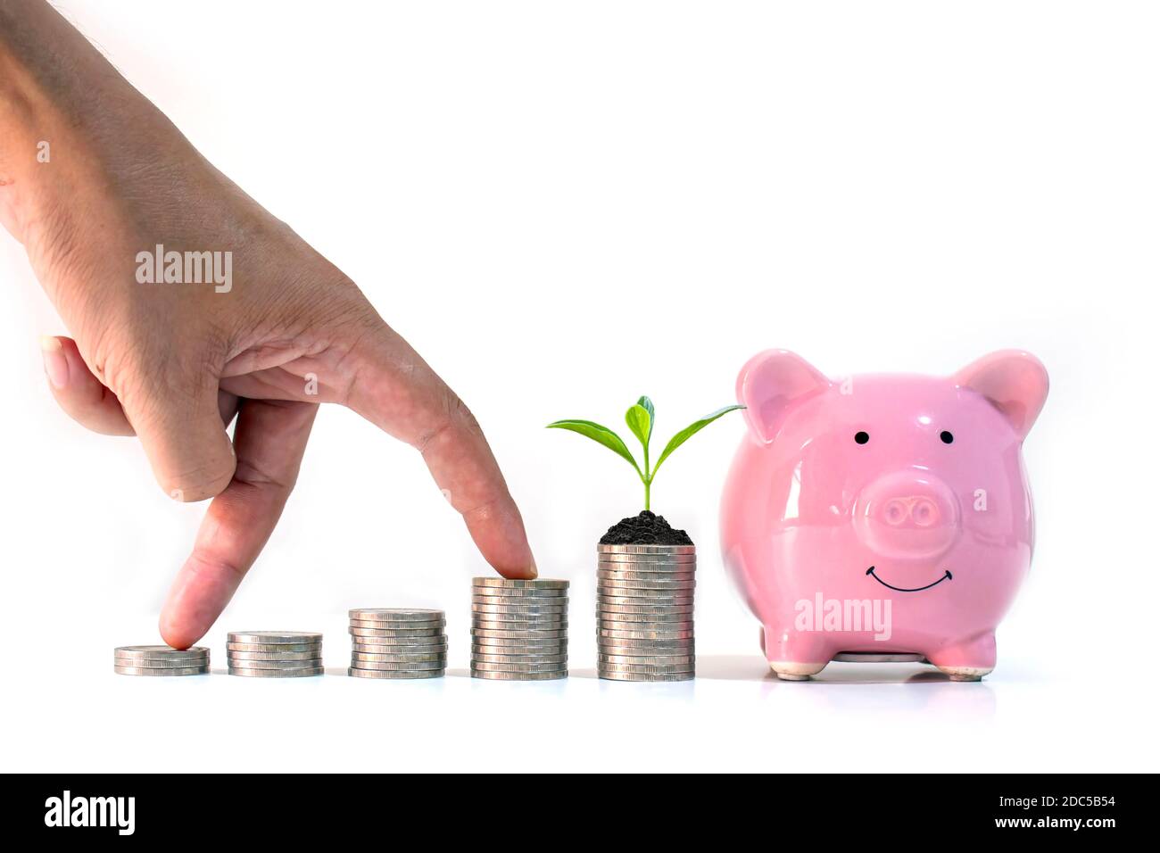 La mano dell'investitore maschio è posta su un mucchio di monete e alberi che crescono su un mucchio di monete e. piggy bank su fondo bianco concept bus per risparmiare denaro Foto Stock