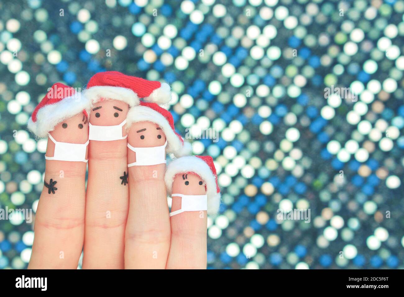 Fingers arte di famiglia in maschera medica da COVID-2019 celebra il Natale. Concetto di persone in cappelli di Capodanno. Foto Stock
