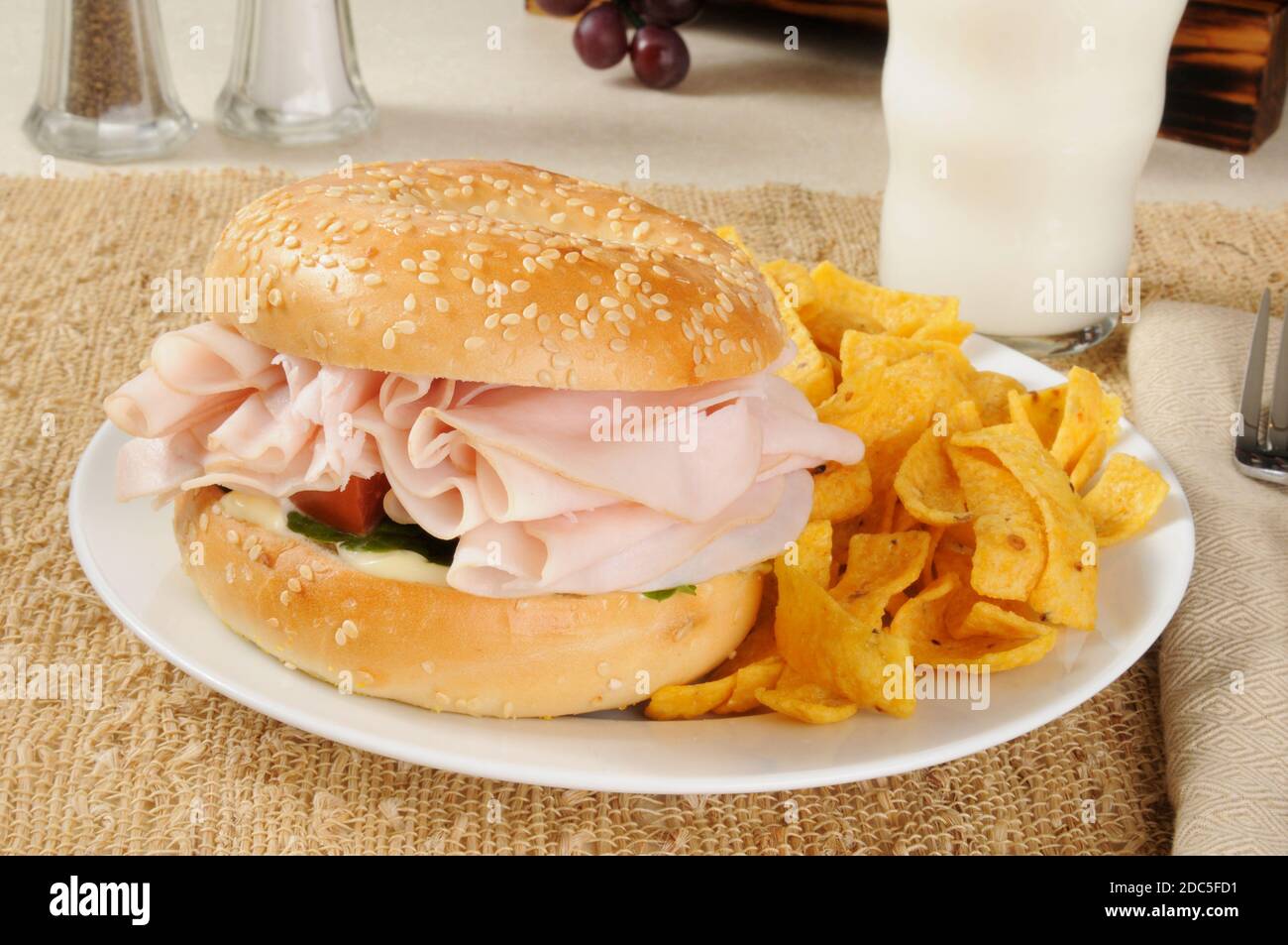 Un panino di prosciutto su un bagel con patatine di mais Foto Stock