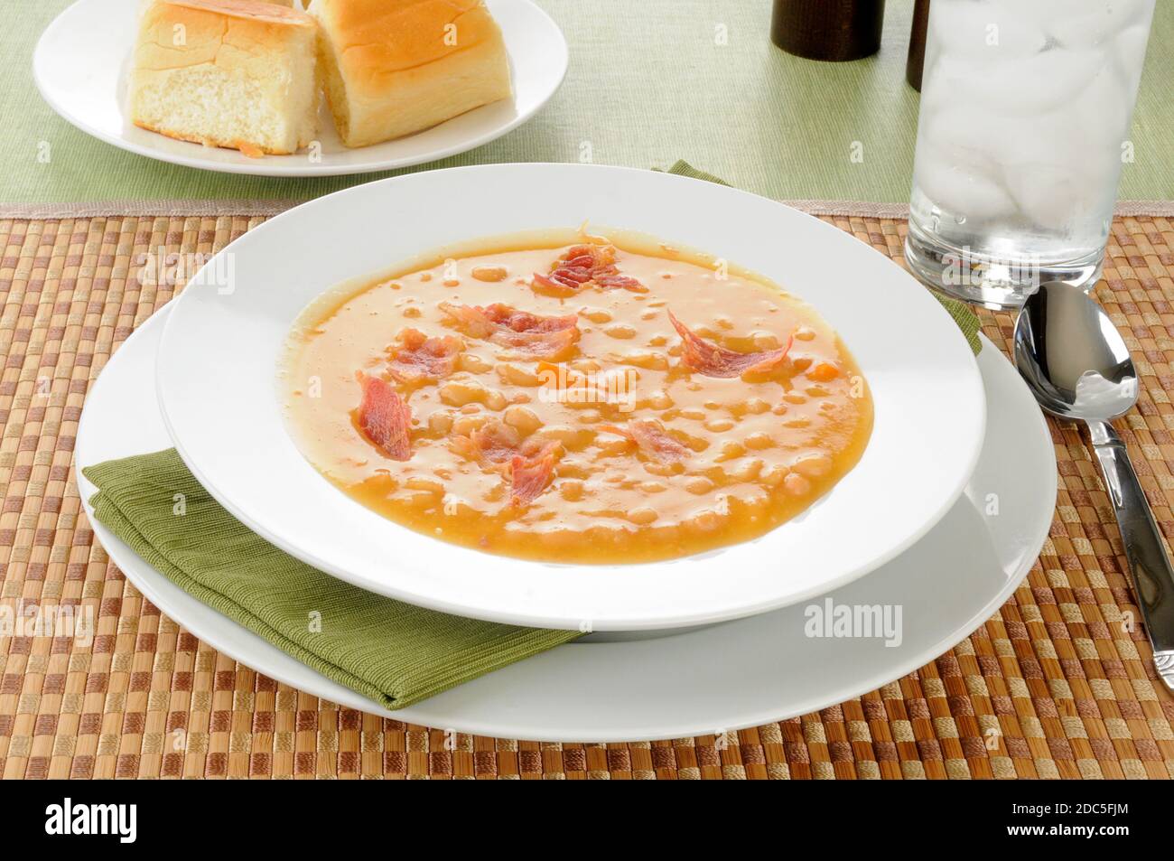 Una ciotola di zuppa di fagioli e pancetta con panini per cena Foto Stock
