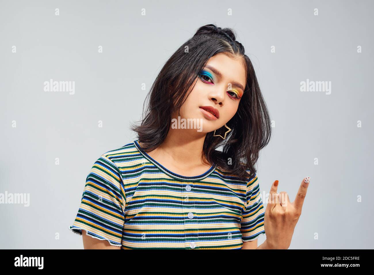 Crazy bella rock ragazza. Punk non è morto. Attraente giovane donna fredda che fa il gesto della mano del segno del corno. Foto Stock