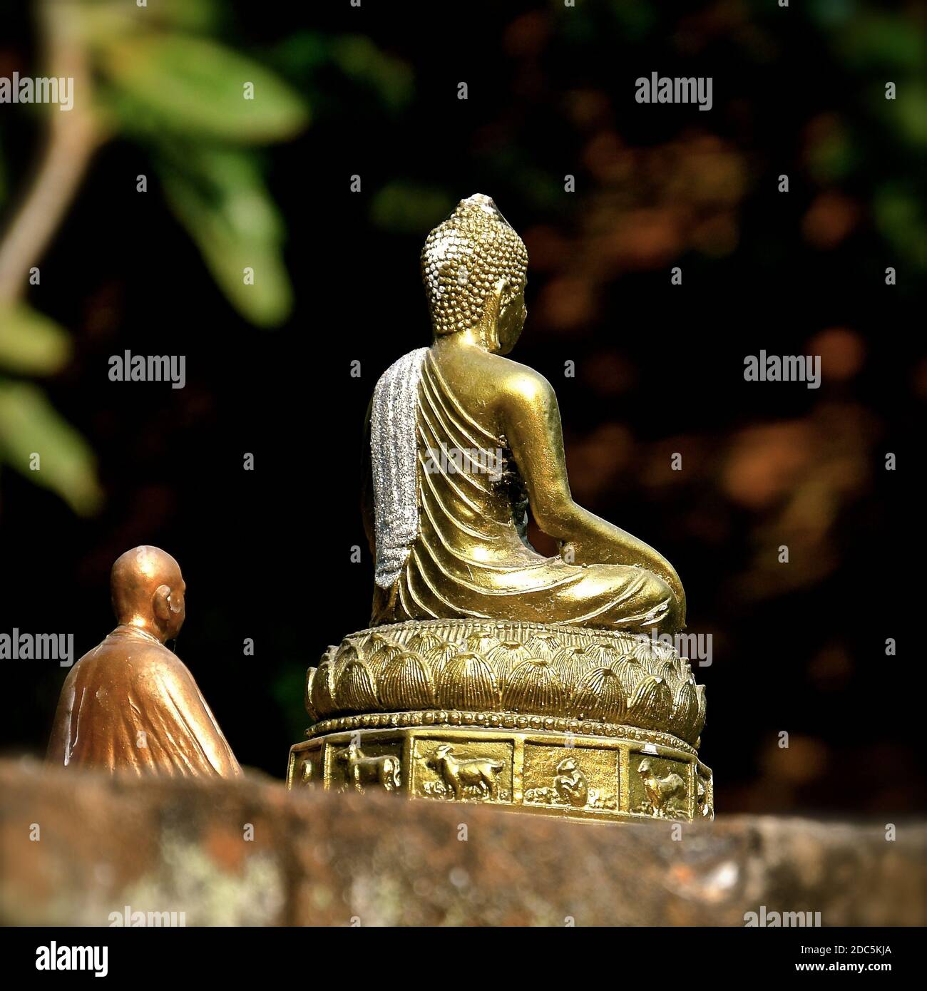 Una vista posteriore di una statua di ottone di Buddha meditando mentre si siede in posizione di loto. Foto Stock