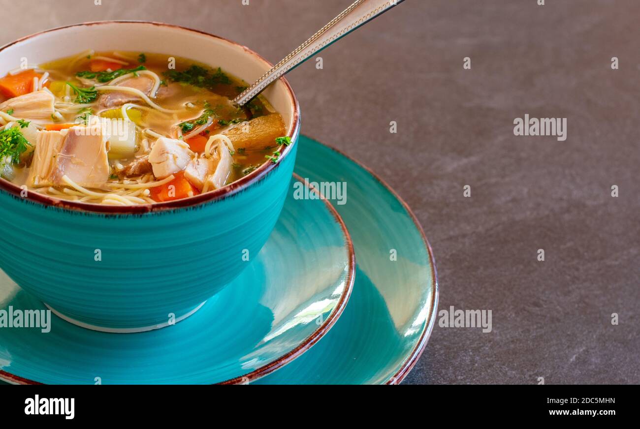 una ciotola di zuppa di noodle di pollo appena cotta con cucchiaio isolato su un tavolo Foto Stock