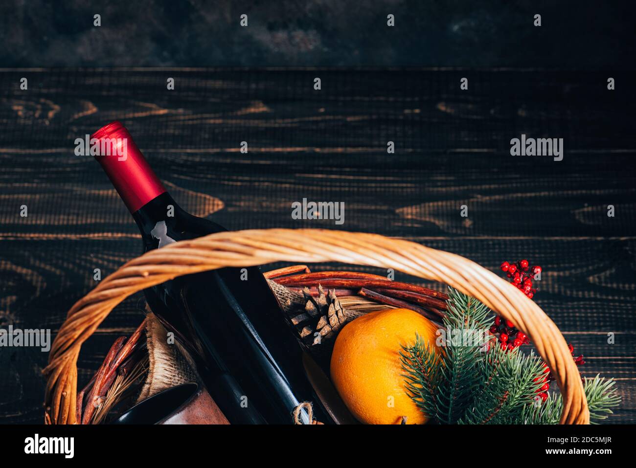 Bottiglia di vino rosso nel cestino regalo di Natale. VIN brulé con arance, coppe e ornamenti di abeti in scatola. Vista dall'alto Foto Stock