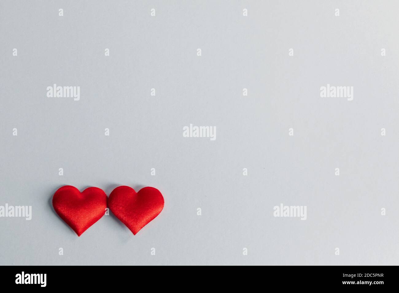 San Valentino due cuori di seta rossa su sfondo grigio carta, concetto di amore Foto Stock