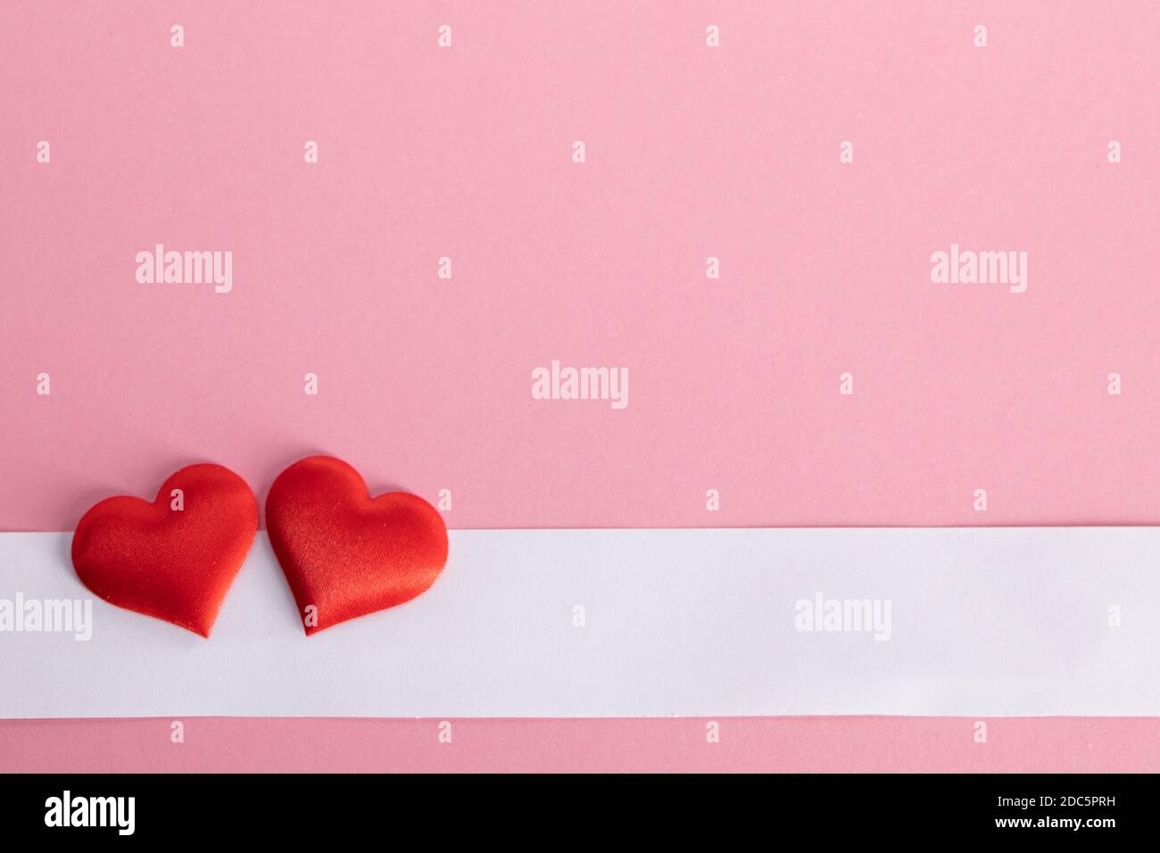 San Valentino due cuori di seta rossa e carta bianca su sfondo di carta rosa, concetto di amore Foto Stock