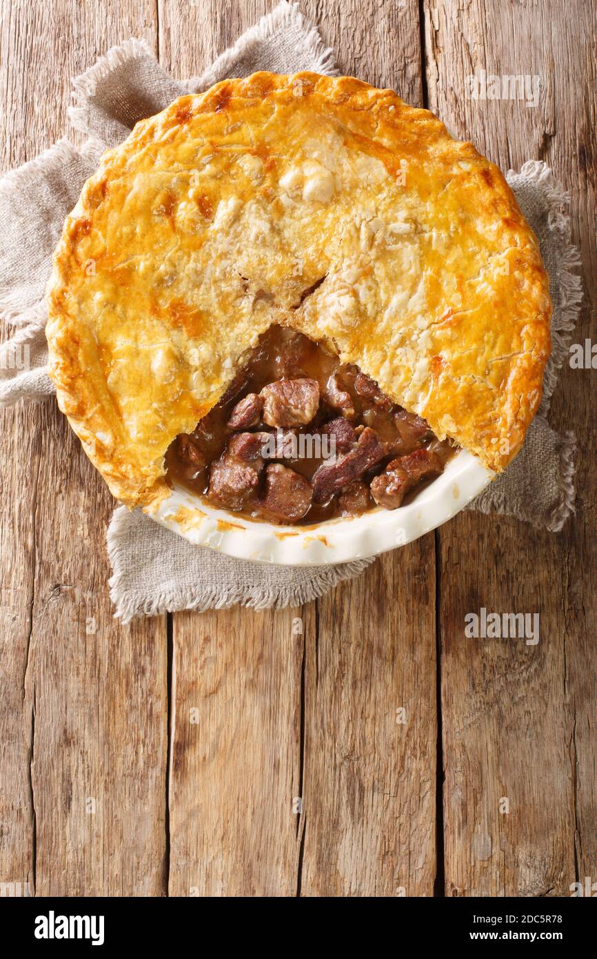 Deliziosa torta di bistecca inglese tradizionale da primo piano in una teglia sul tavolo. Vista dall'alto verticale Foto Stock