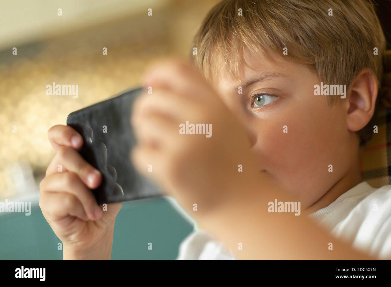 Primo piano ragazzo focalizzato giocare video gioco su smartphone Foto Stock