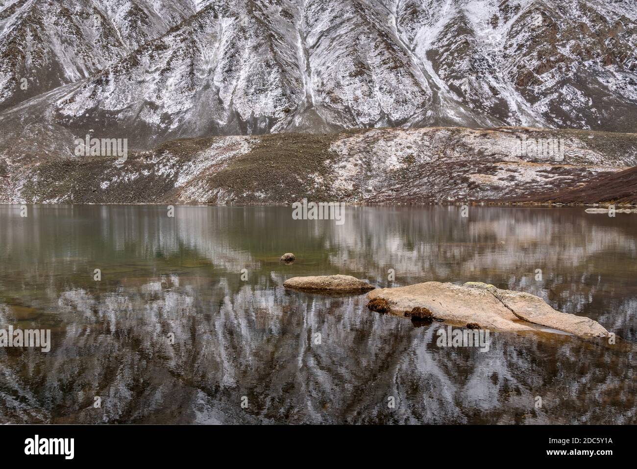 Pittoreschi riflessi speculari delle montagne ricoperte dalla prima neve nelle acque lisce del lago in autunno Foto Stock