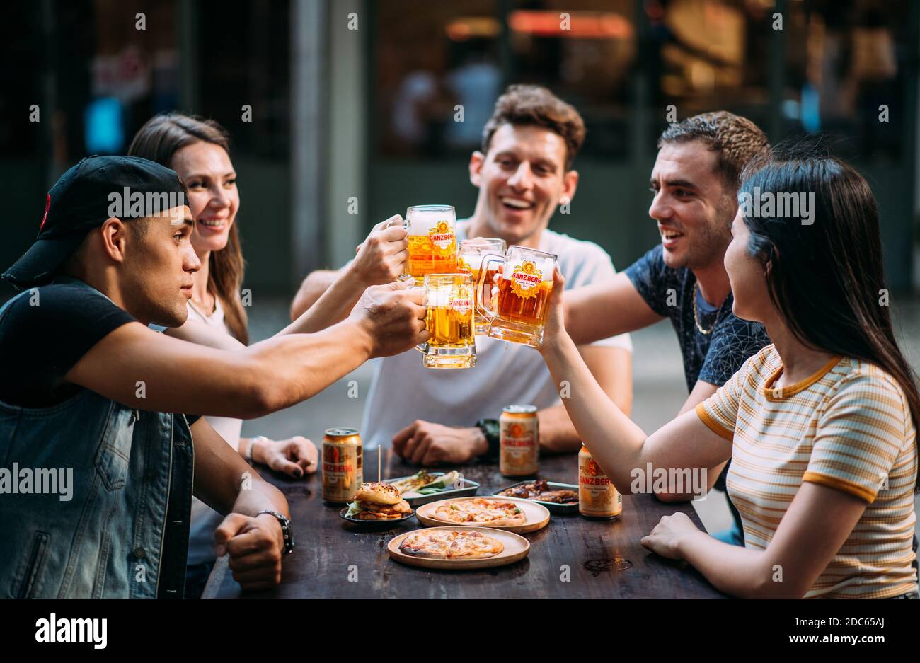 Party birra con gli amici bere birra Ganzberg e tostare birra presso il bar ristorante birreria. Concetto di amicizia con i giovani che si divertono insieme. Foto Stock