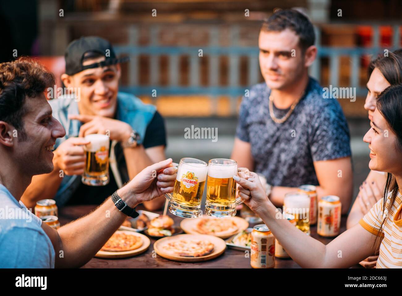 Party birra con gli amici bere birra Ganzberg e tostare birra presso il bar ristorante birreria. Concetto di amicizia con i giovani che si divertono insieme. Foto Stock