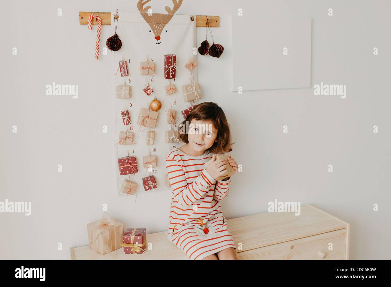 Carino ragazza apertura Natale Avvento doni calendario. Regali avvolti per bambini. Tradizione stagionale. Natale ecologico Foto Stock