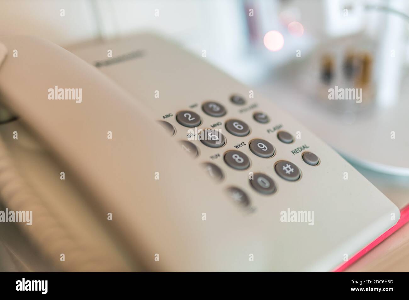 Primo piano, con un'illuminazione soffusa e tecnologia di comunicazione, sui dispositivi telefonici alla scrivania dell'ufficio Foto Stock