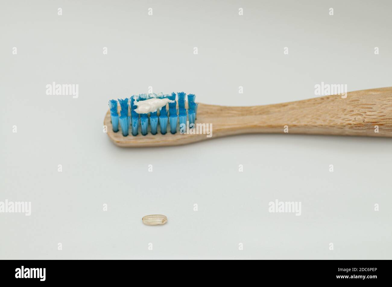 Un primo piano di uno spazzolino da denti in legno con il consigliato dentifricio Foto Stock