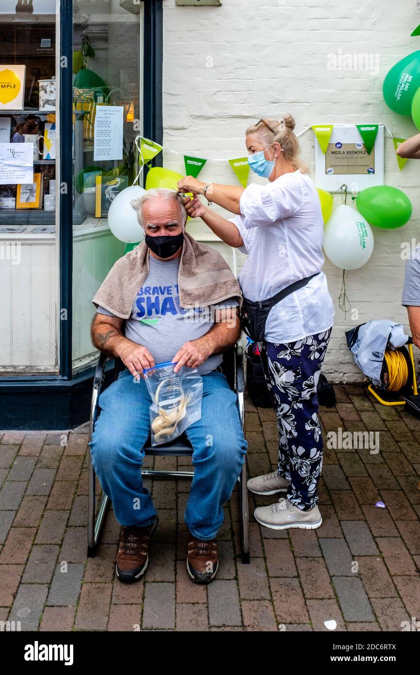 Gli uomini che hanno i loro capelli si sono radunati fuori per raccogliere i soldi per la carità di cura del cancro di Macmillan, High Street, Lewes, Sussex orientale, Regno Unito. Foto Stock