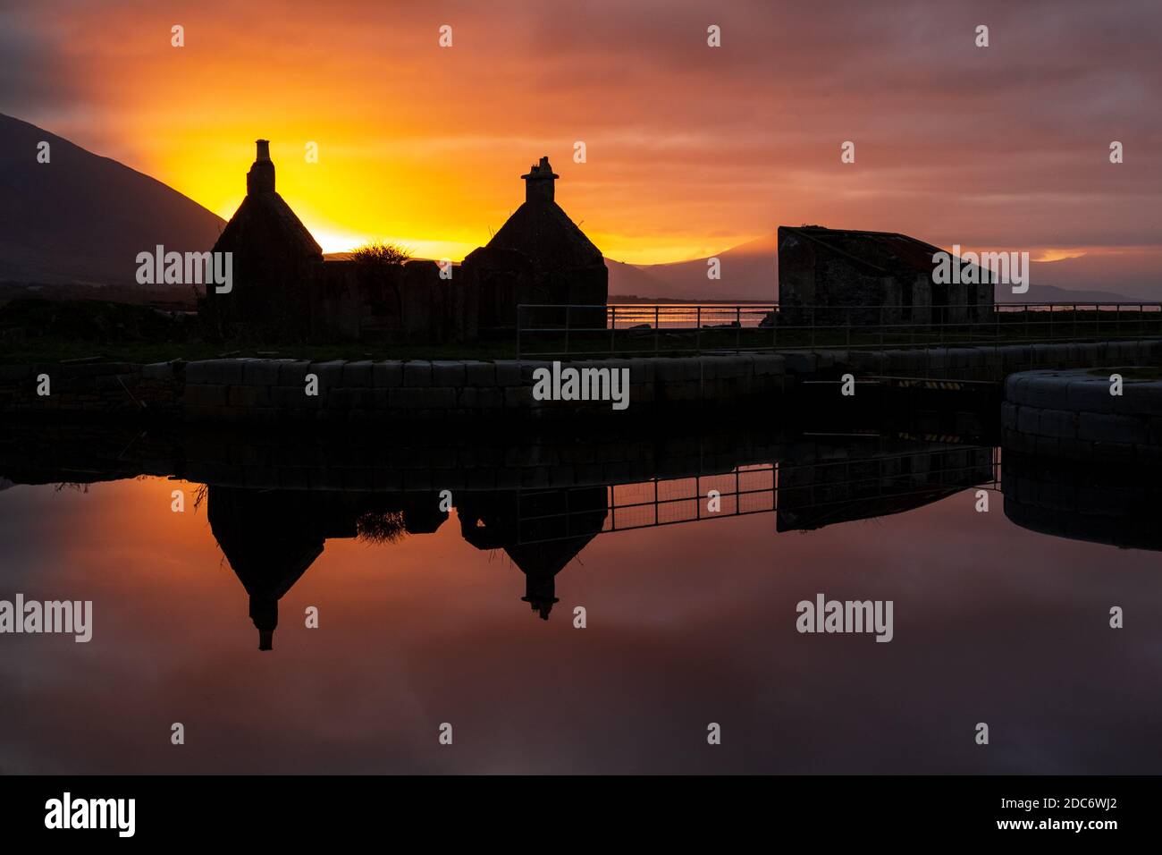 Riflessione di Silhouette di rovinato Cottage e Shed in Canal Water al tramonto a Tralee, Contea di Kerry, Irlanda Foto Stock