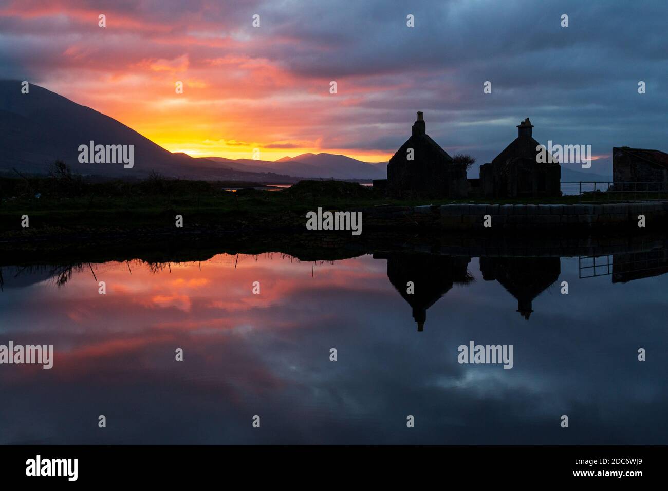 Riflessione di Silhouette di rovinato Cottage e cielo al tramonto in calmo canale acqua a Tralee, Irlanda Foto Stock