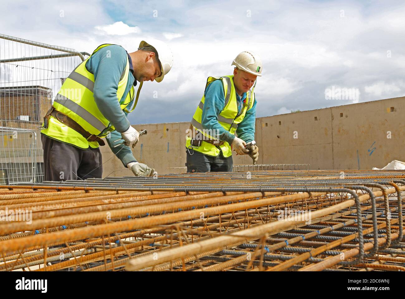 Due operai edili assemblano una gabbia di rinforzo in acciaio per Calcestruzzo in situ su un grande edificio londinese Foto Stock