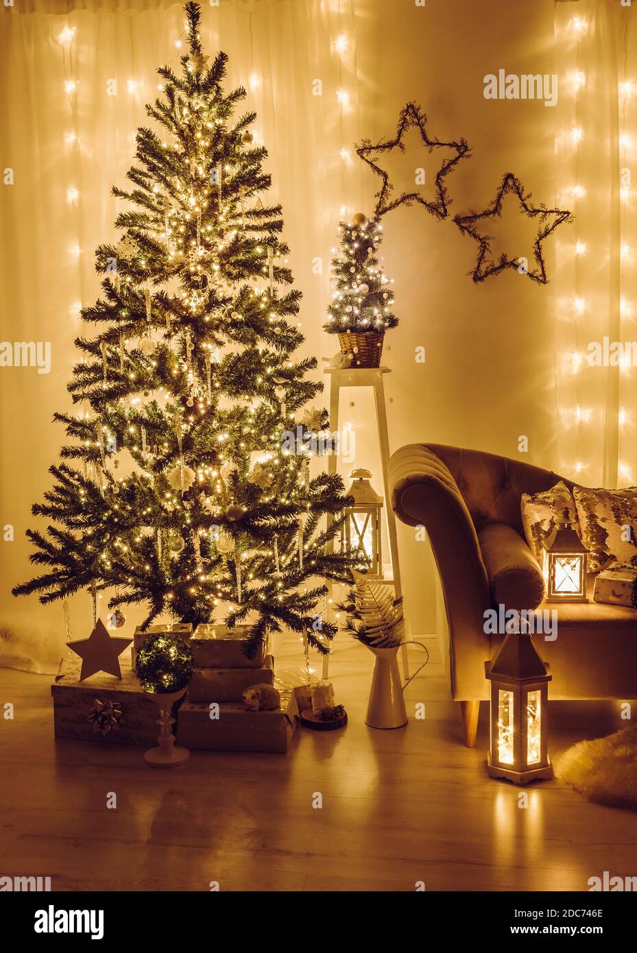 Soggiorno a casa decorato per la vigilia di Natale. Albero di abete rosso di Natale decorato con luci di festa, iciclette e fiocchi di neve, avvolti regali di Natale. Foto Stock
