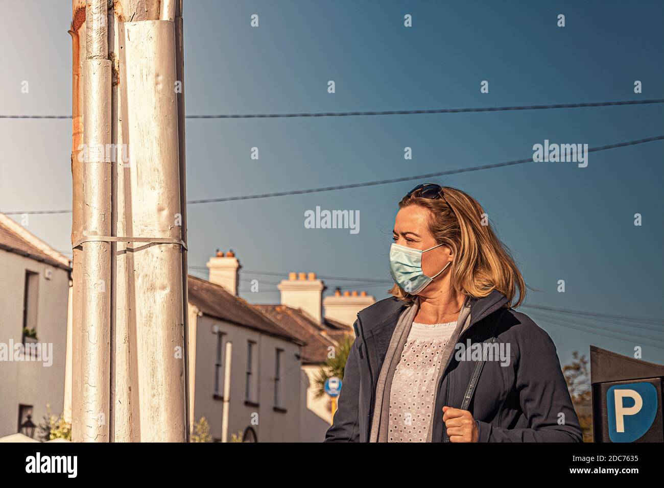 Vita quotidiana. Donna in maschera di protezione del viso che cammina la strada che raggiunge verso la fotocamera di fronte. Foto Stock