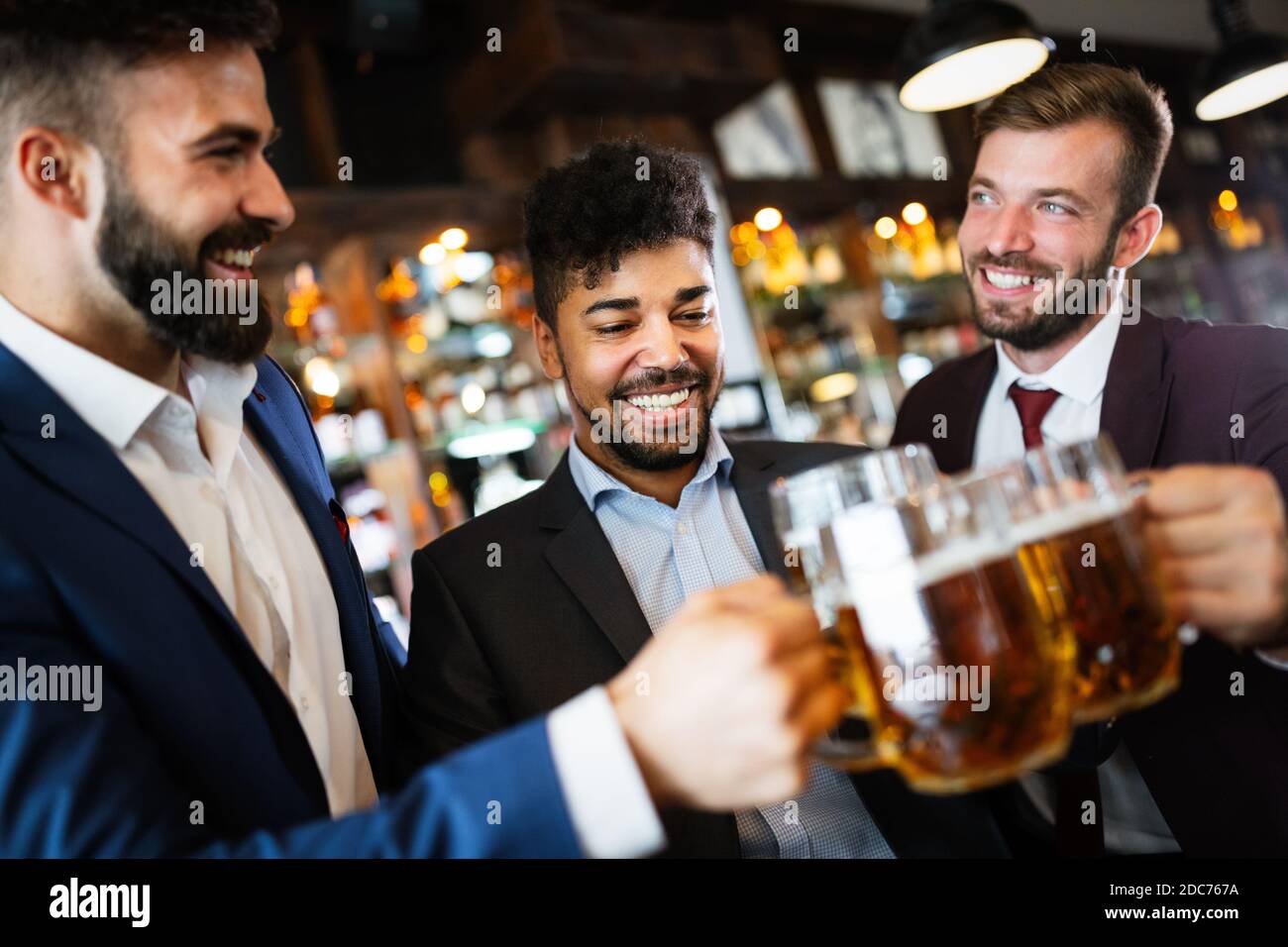 Vecchi amici allegri che si divertono e bevono birra al banco bar nel pub. Foto Stock