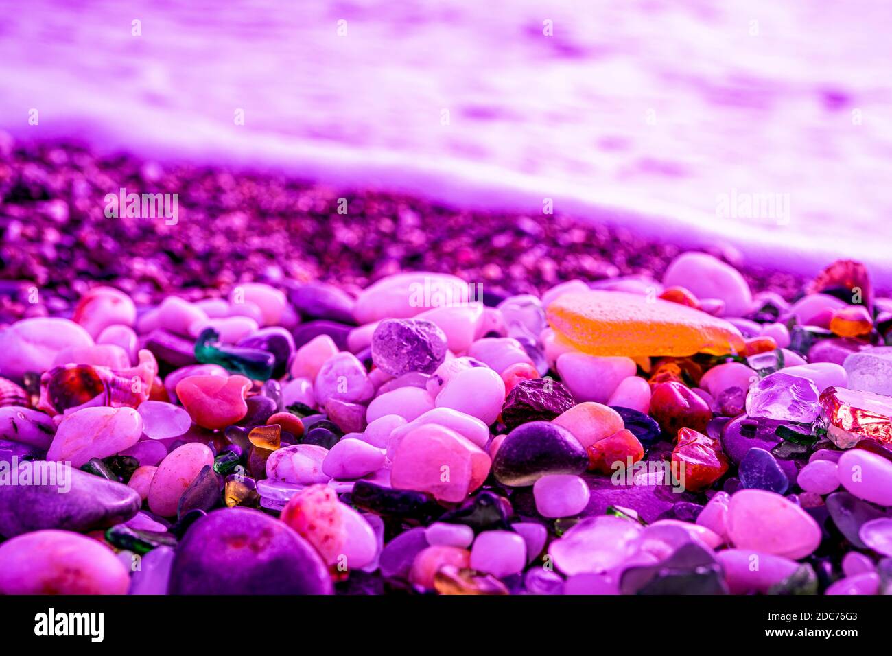 Colorato vetro marino trovato sulla costa in luce fluorescente cremisi. Foto di alta qualità Foto Stock