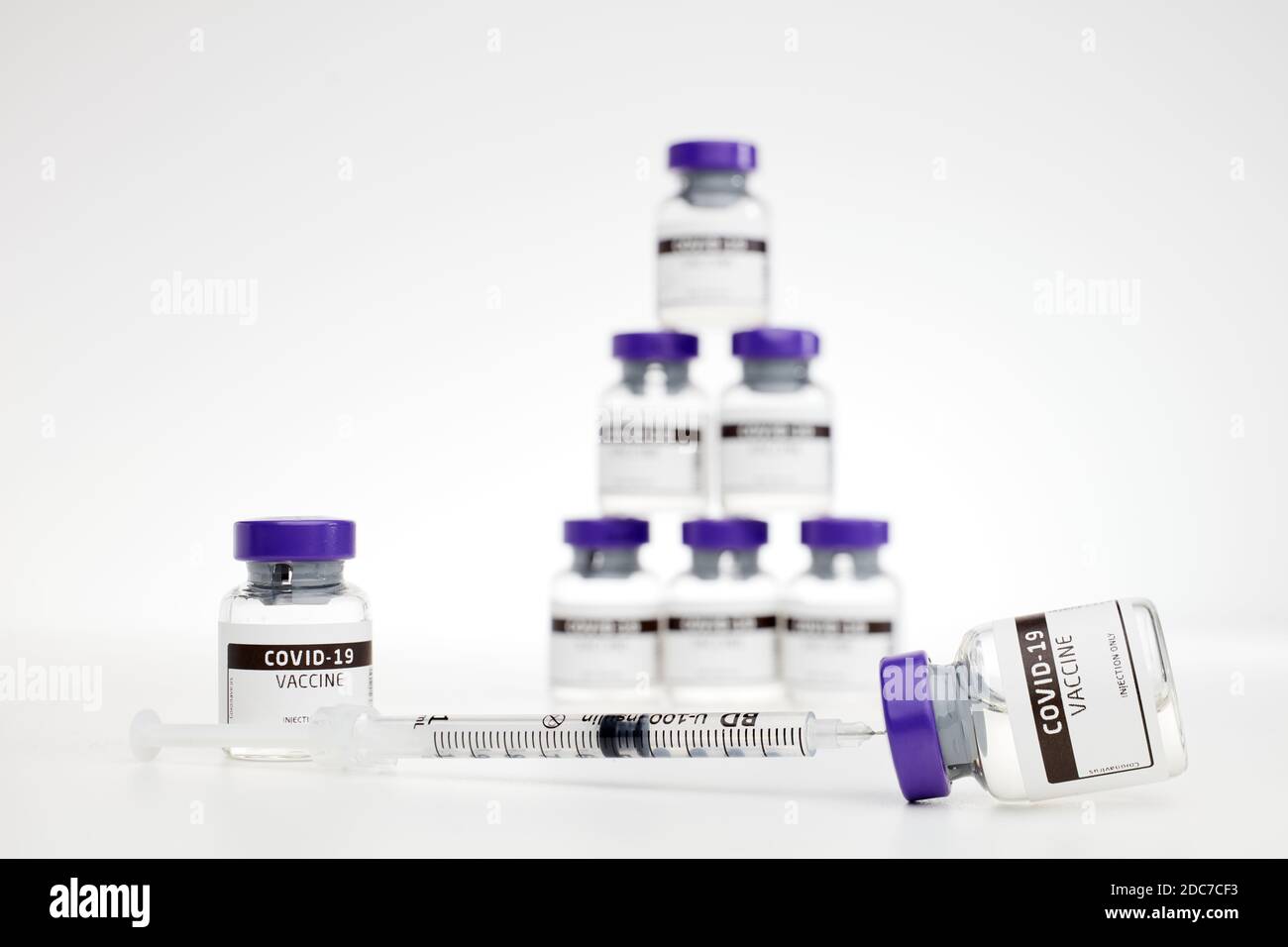 Closeup di fiale di vaccino per il trattamento di coves-19 / coronavirus, raffigurato con una siringa su sfondo bianco Foto Stock