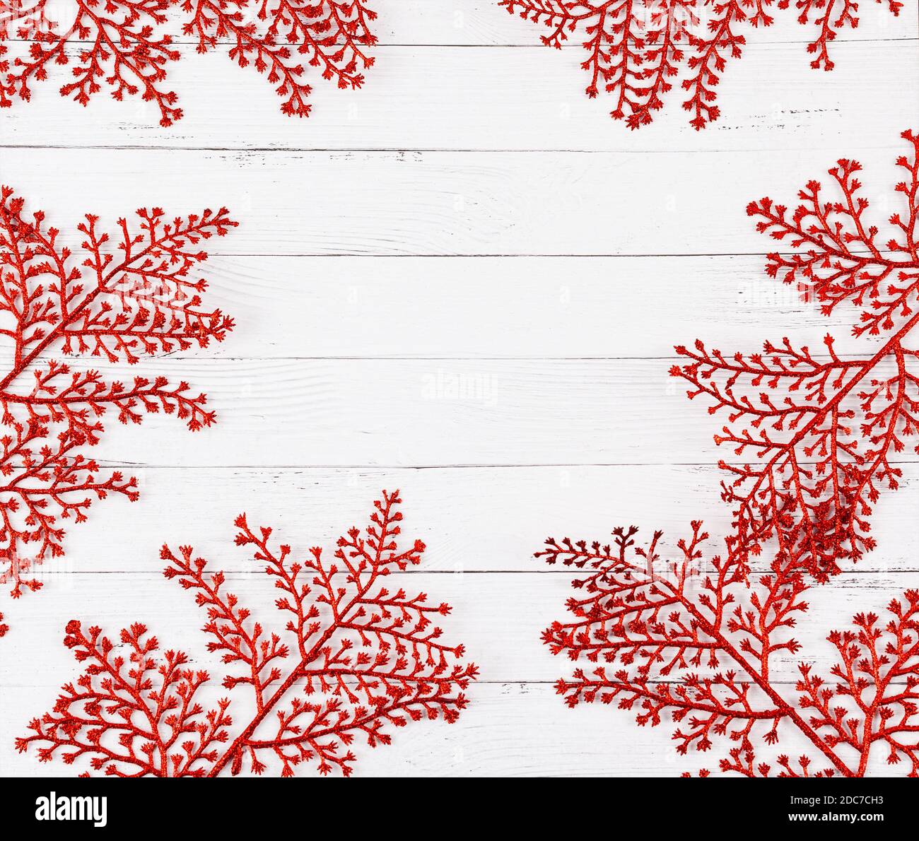 Sfondo bianco di legno per le vacanze di natale con ramificazioni decorative di colore rosso glitter e spazio copia centrale. Foto Stock