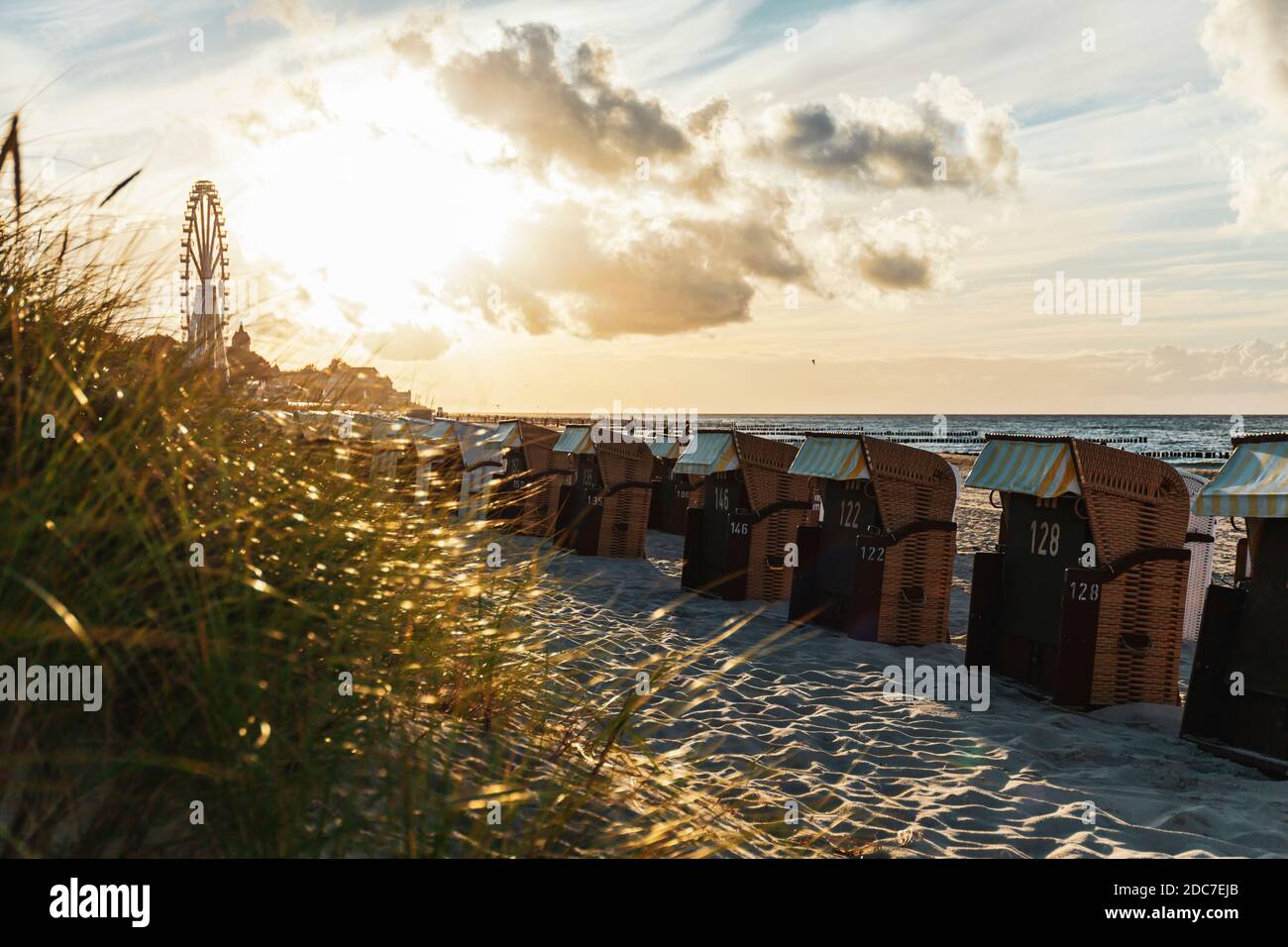 Grande ruota e sedie da spiaggia sulla spiaggia di Kühlungsborn´s in moody retroilluminazione Foto Stock