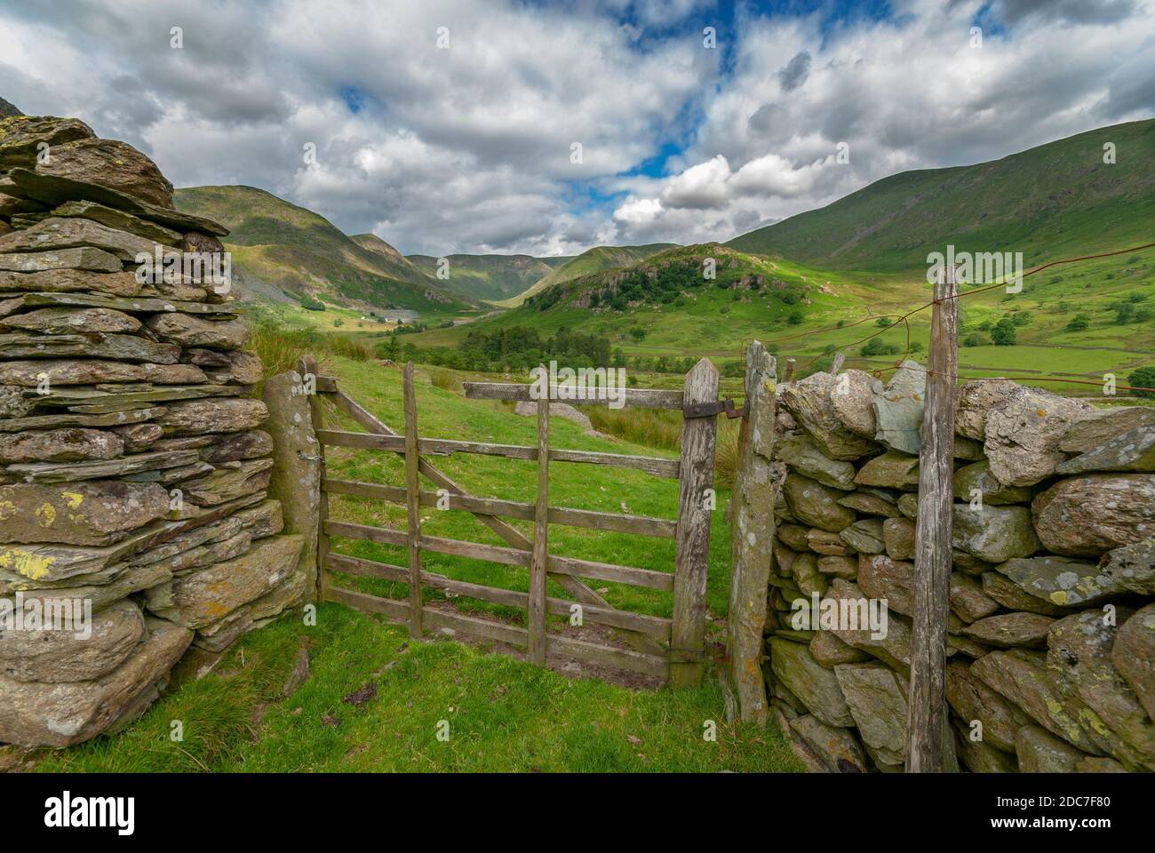 Un'idilliaca scena di campagna inglese con un vecchio cancello rotto sei bar che conduce l'occhio attraverso pascoli verdi a colline lontane e cieli pittoreschi. Foto Stock
