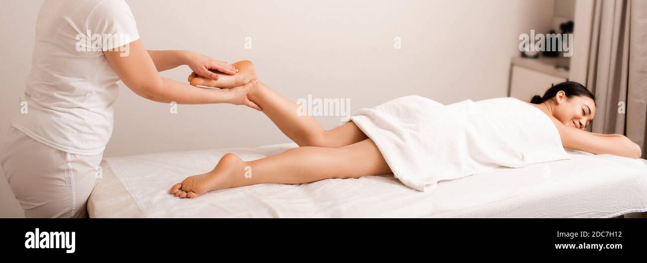 La donna asiatica riceve un massaggio del piede. Il massaggio terapeutico rilassa i muscoli del piede femminile Foto Stock