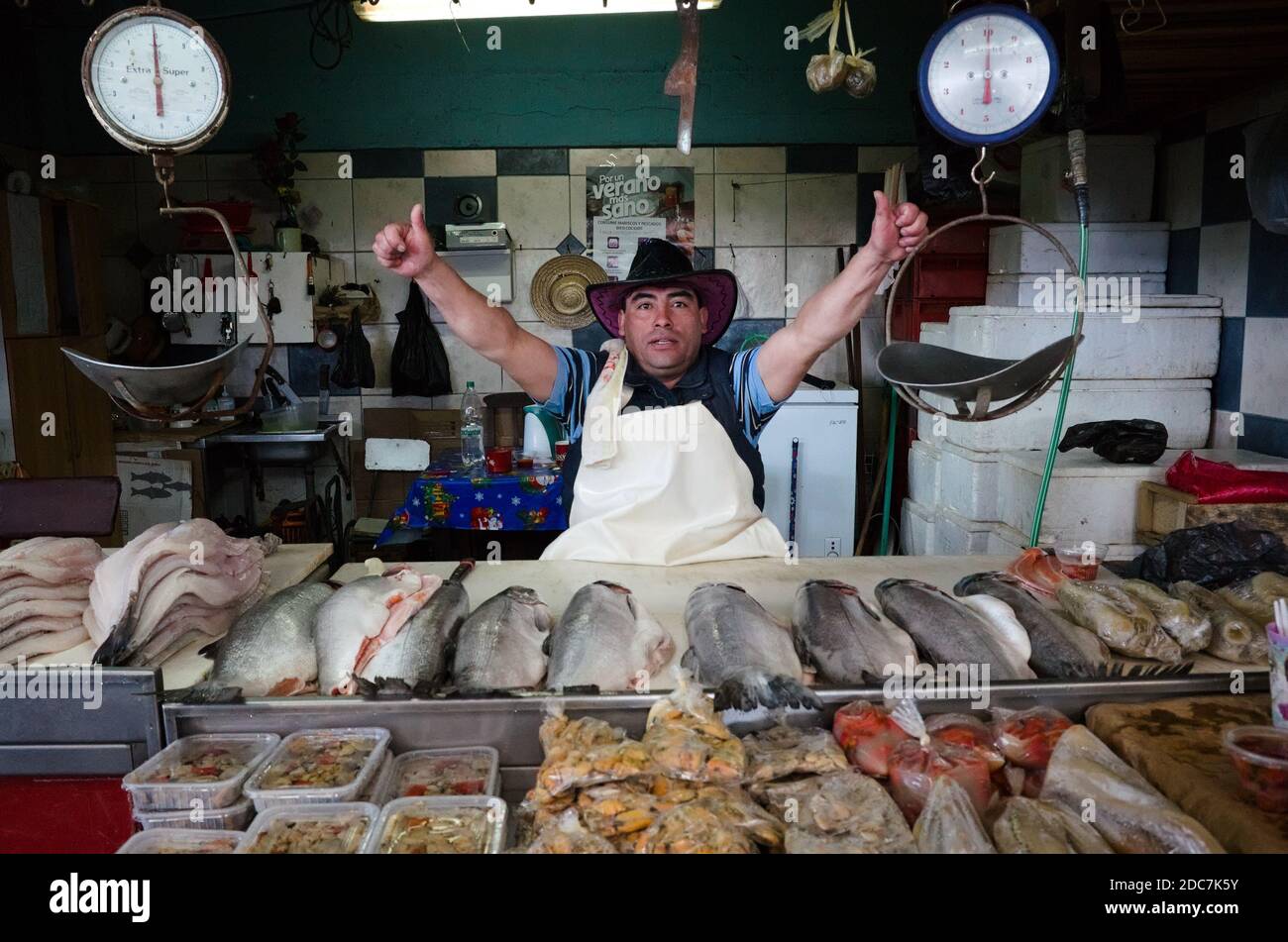 Osorno, Cile - Febbraio, 2020: Venditori vendono diverse cozze di pesce sul mercato locale del pesce. Uomo in cappello guardando la macchina fotografica e mostrare i pollici su beh Foto Stock