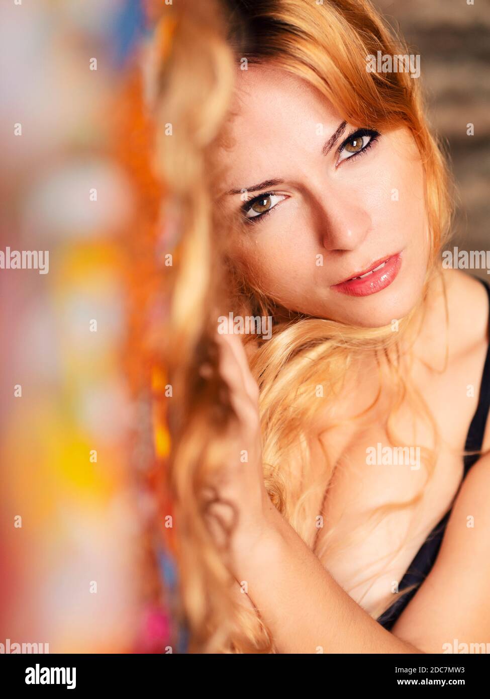 Giovane donna con lunghi capelli biondi sdraiati sul letto, guardando la macchina fotografica Foto Stock