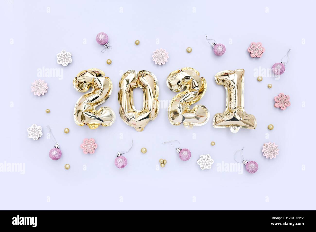 Palloncini d'oro in lamina sotto forma di numeri 2021 e decorazioni festive su sfondo chiaro. Festa di nuovo anno. Decorazione festa. Foto Stock