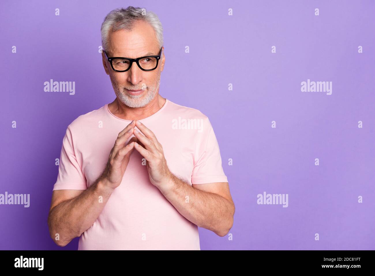 Foto di vecchio uomo in pensione tenere le braccia guardare lato copyspace indossare occhiali rosa t-shirt isolato colore viola sfondo Foto Stock