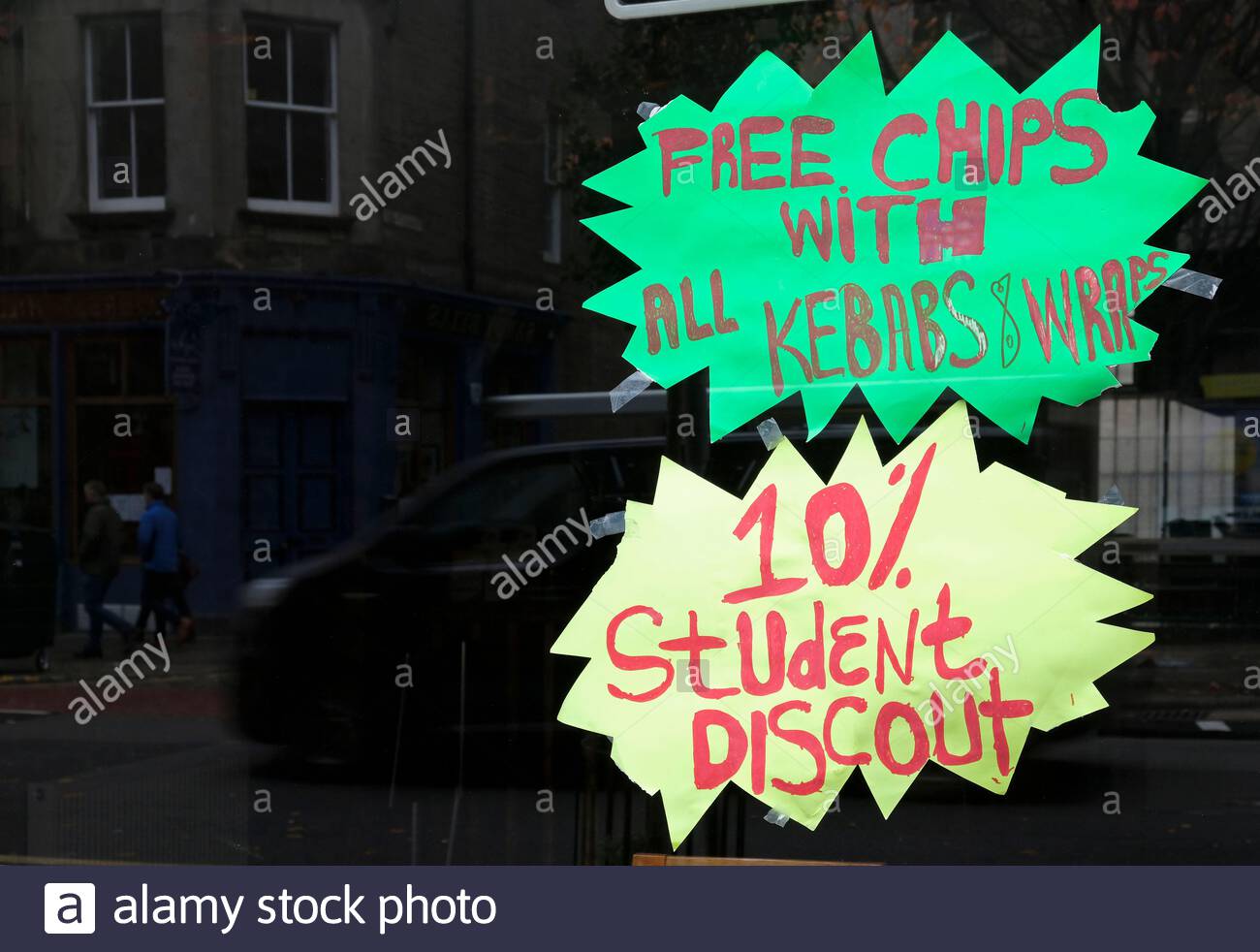 Patatine gratuite con kebab e wrap con un cartello dello sconto del 10% per studenti, nella vetrina di un negozio di Fish and Chip, Regno Unito Foto Stock