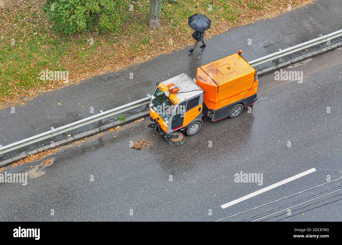 una speciale macchina spazzatrice rimuove le foglie autunnali su una strada cittadina, vista dall'alto Foto Stock