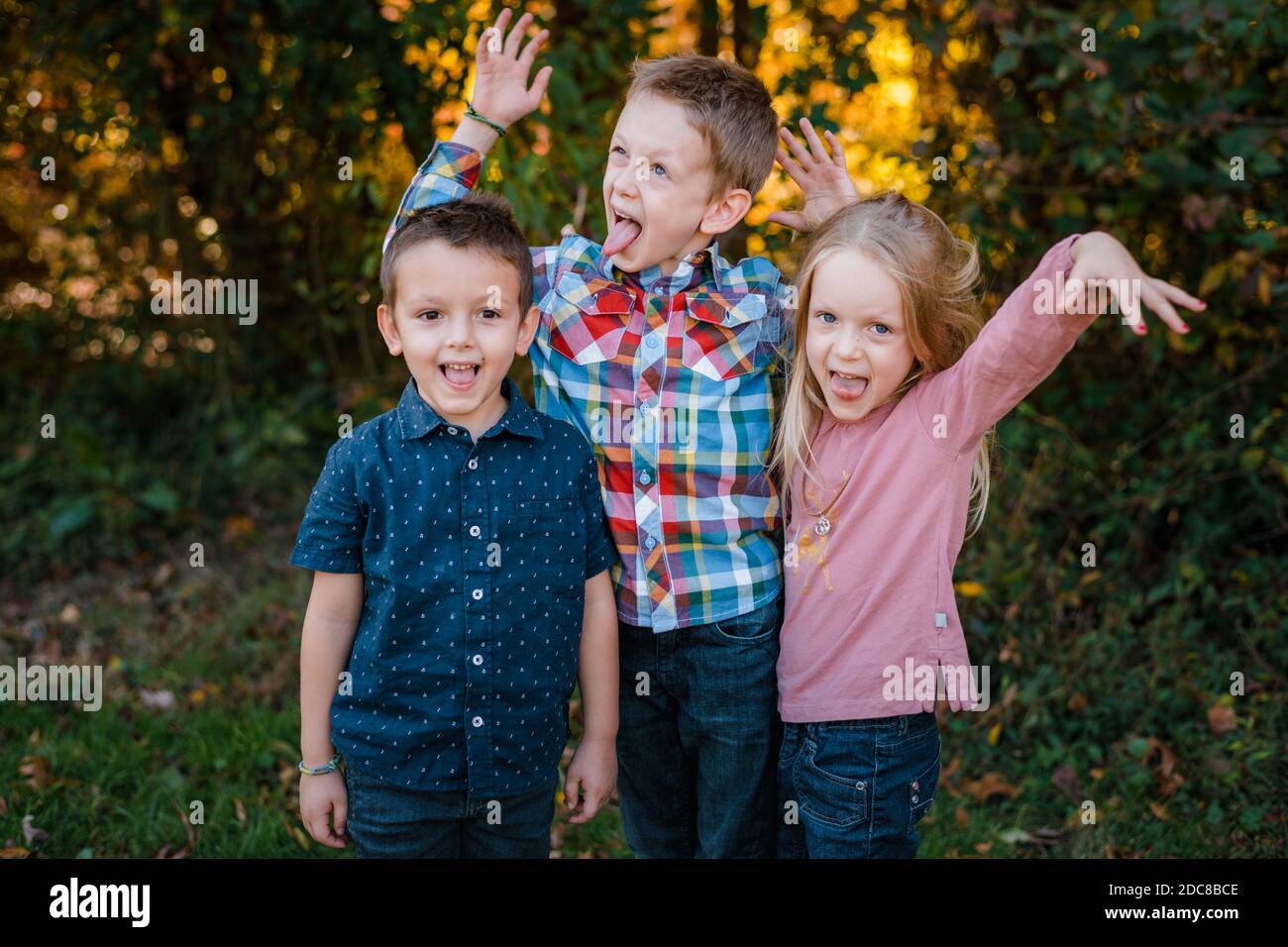 i fratelli di famiglia e la sorella che fanno i volti sciocco che giocano fuori Foto Stock