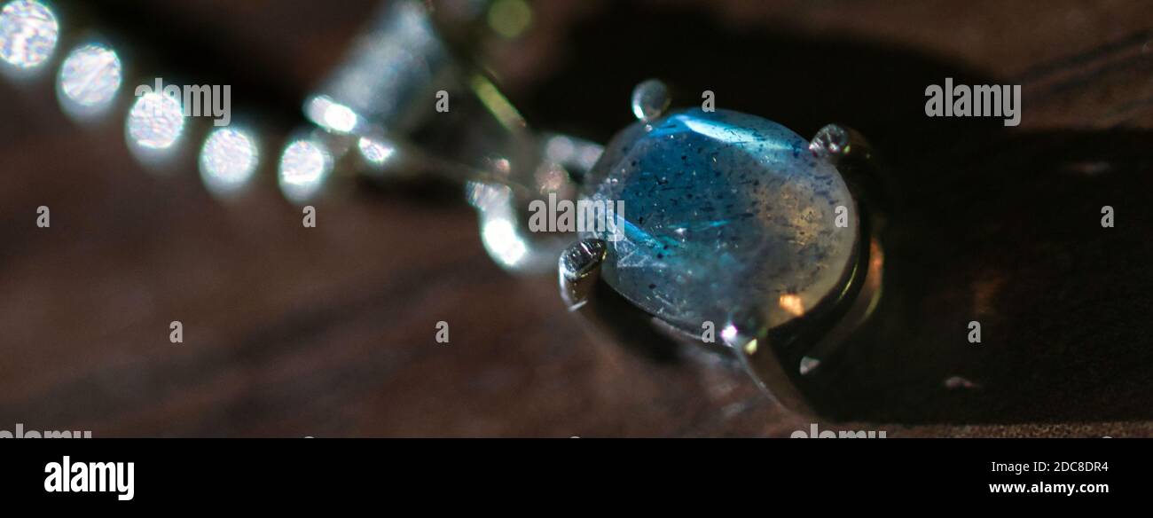 Sfaccettato blu scintillante labradorite cristallo vecchia collana su una superficie di legno marrone scuro, luce e ombre contrasti, magia, mistica, cristallo guarigione a Foto Stock